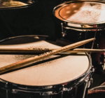 pair of brown wooden drumsticks on top of white and gray musical drum